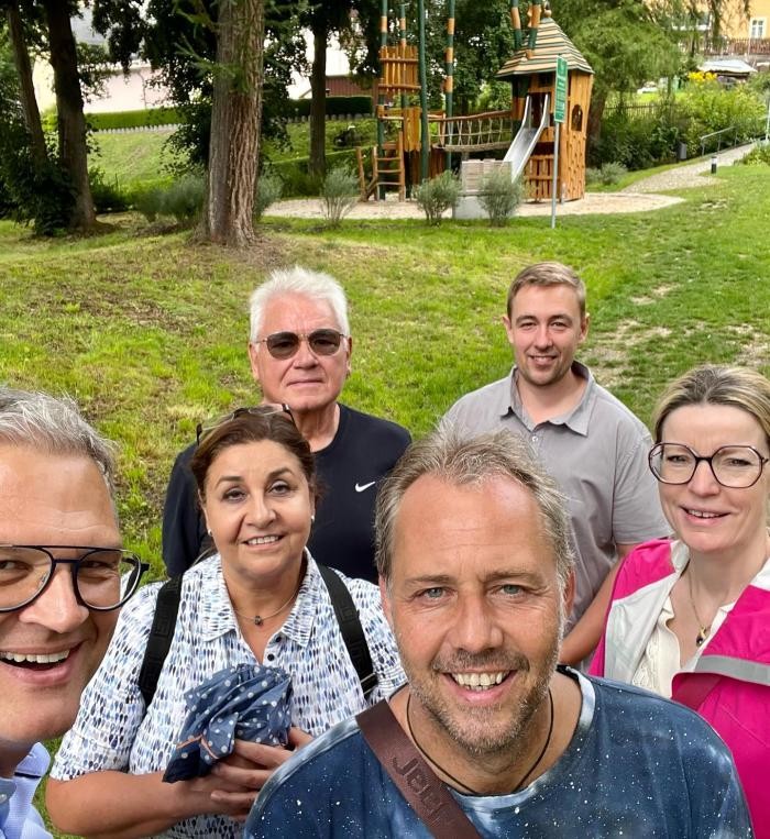 Sechs Personen stehen vor einem Spielplatz.