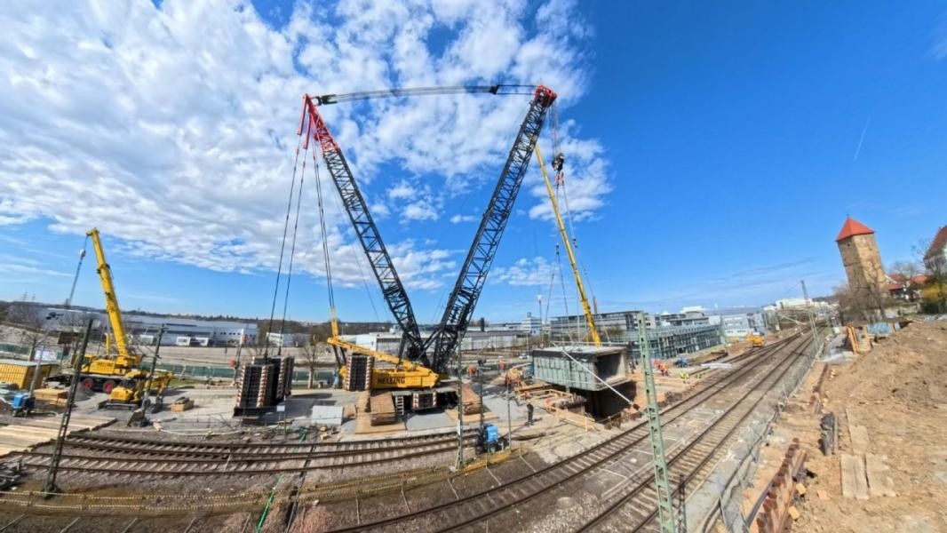 Ein Baukran hebt auf der Baustelle am Bahnhof ein Rahmenbauteil ein.