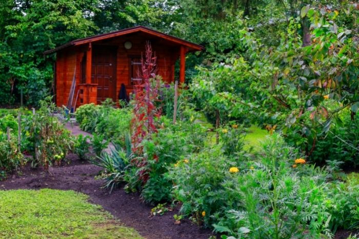 Ein rotes Gartenhaus steht inmitten eines Gartens.