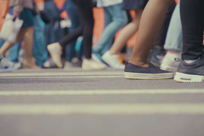 Foto: Adobe Stock Viele Personen laufen auf einer Straße. Sie sind knieabwärts abgebildet.